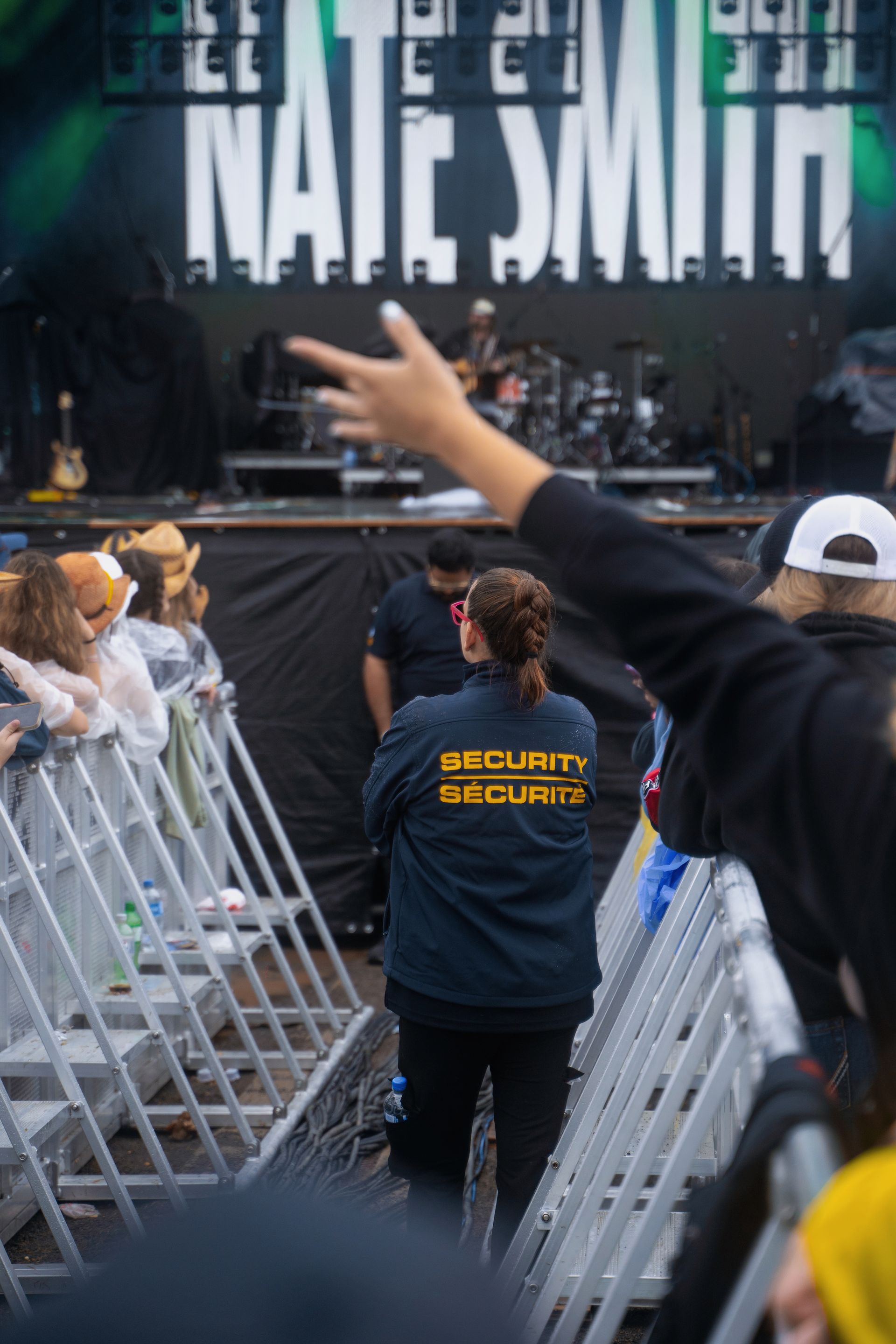 A security guard is standing in front of a crowd of people at a concert.