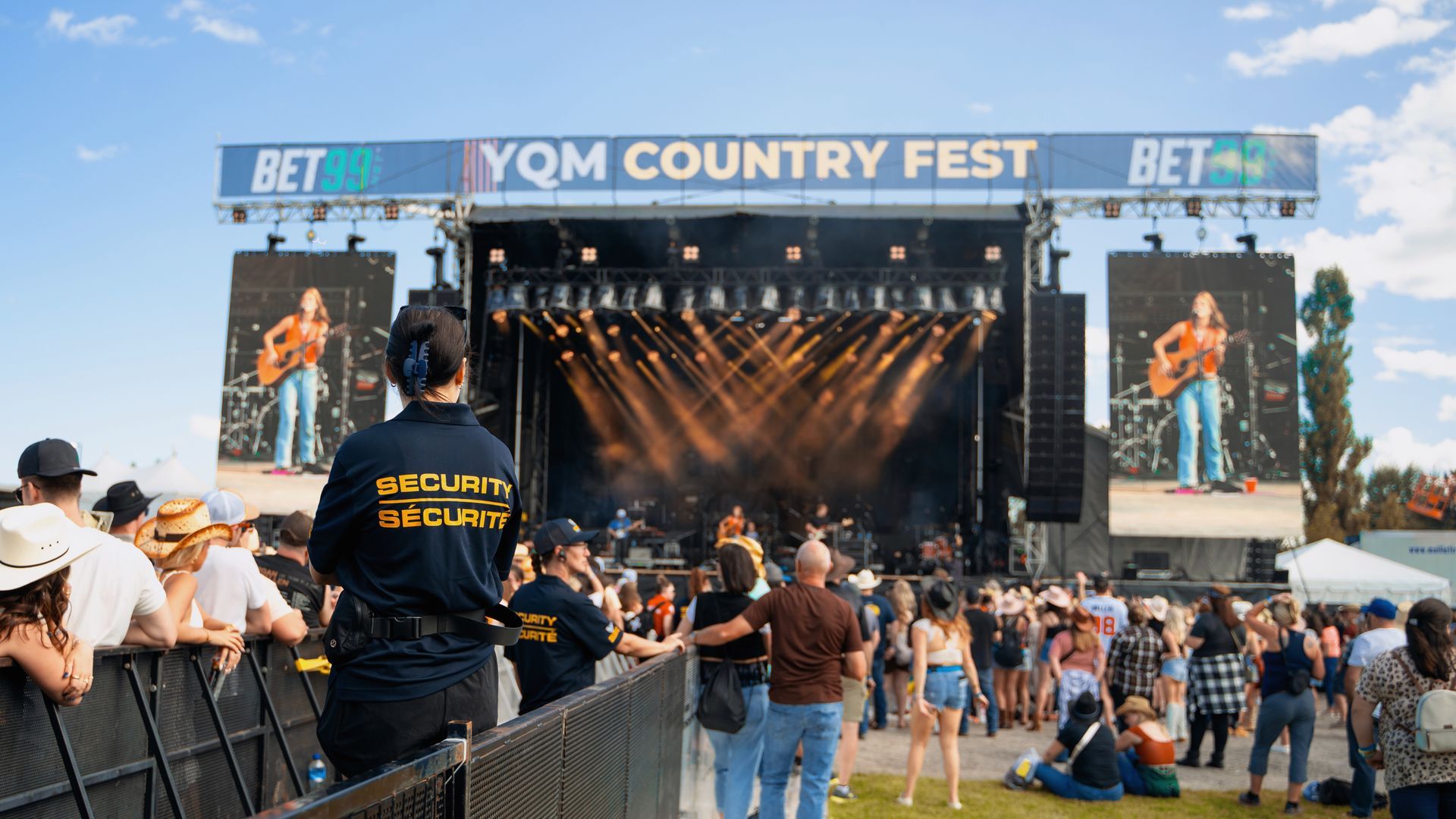 A group of people are standing in front of a stage at a country music festival.