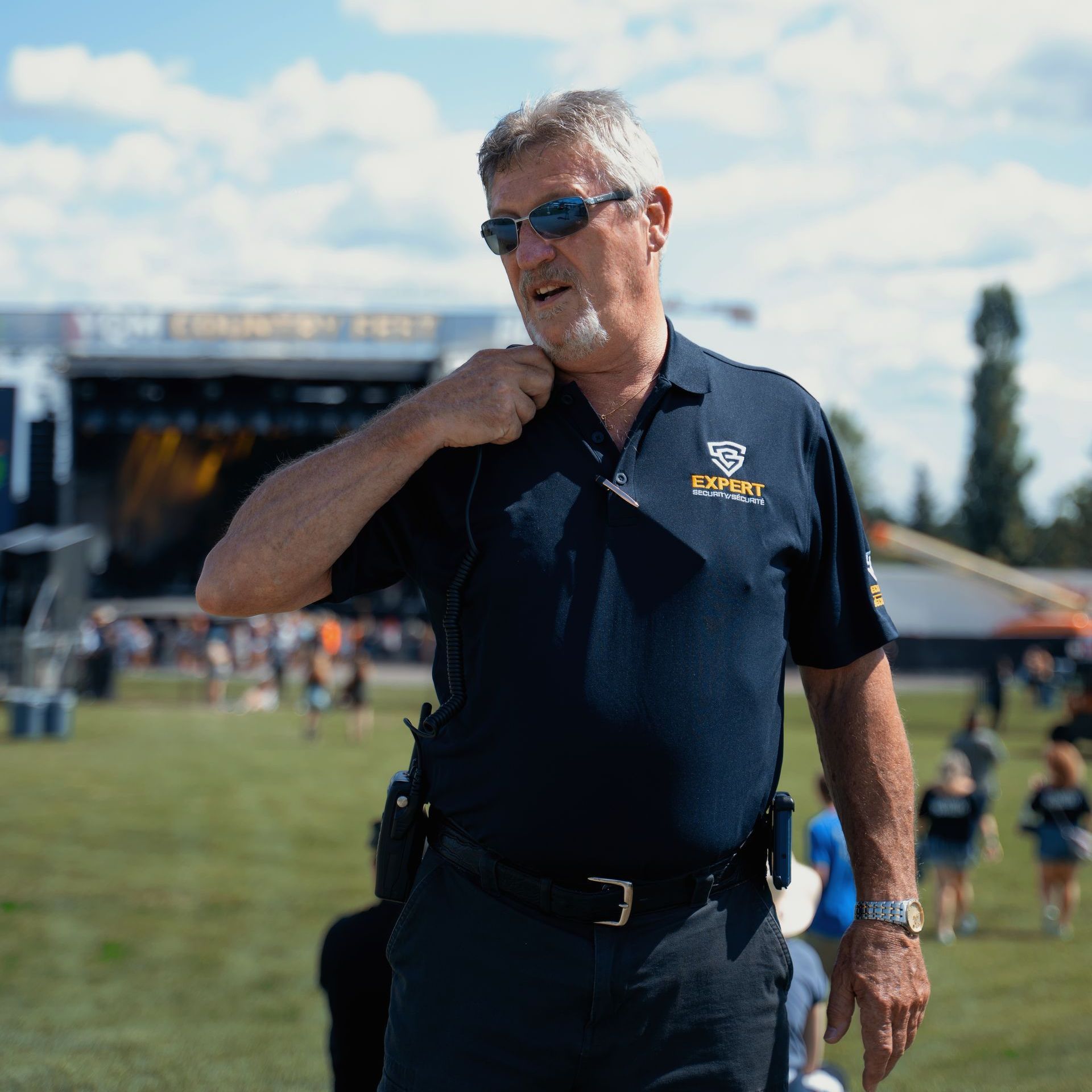 A man wearing sunglasses and a shirt that says ' security ' on it