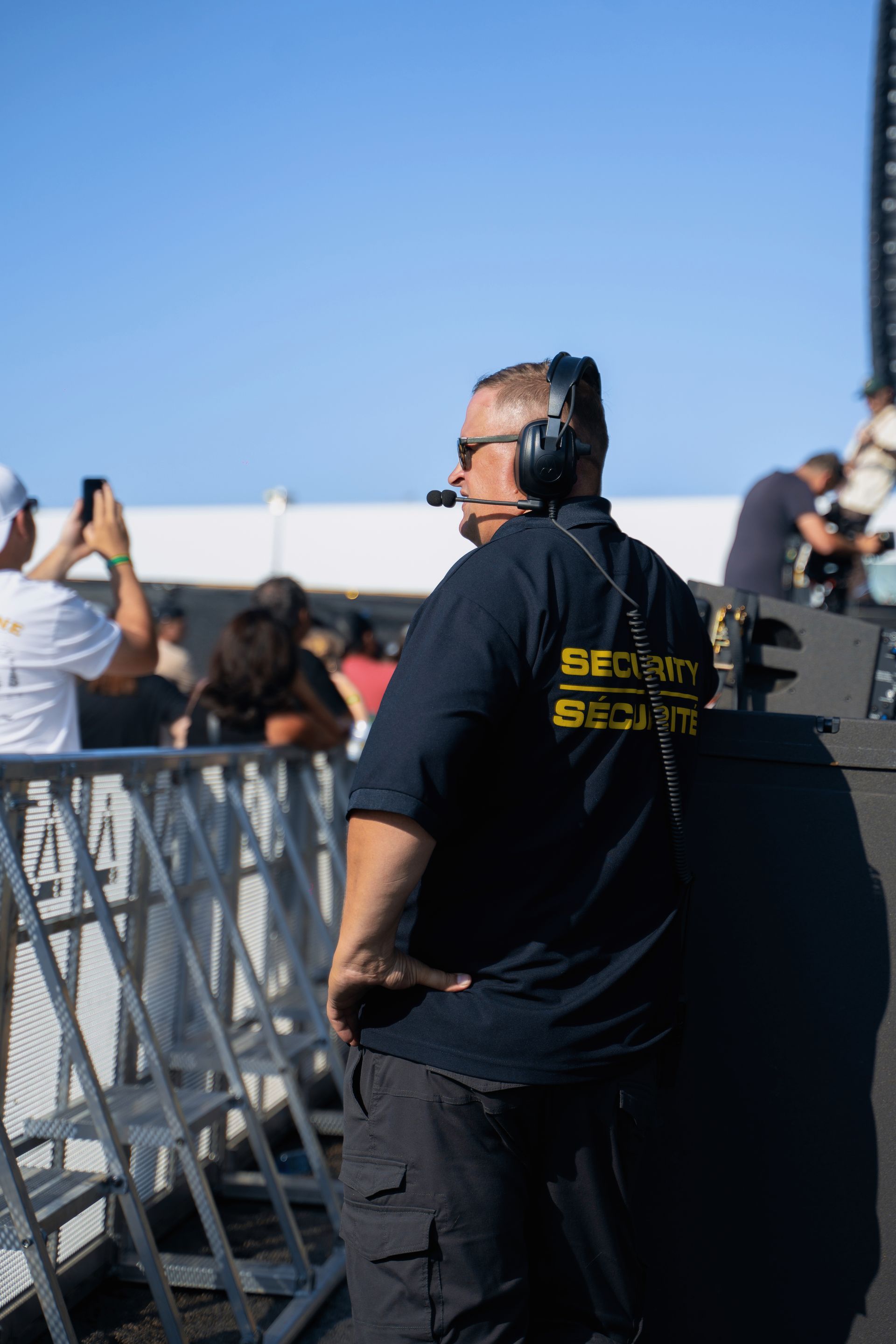 A man wearing headphones and a microphone is kneeling down in front of a crowd.