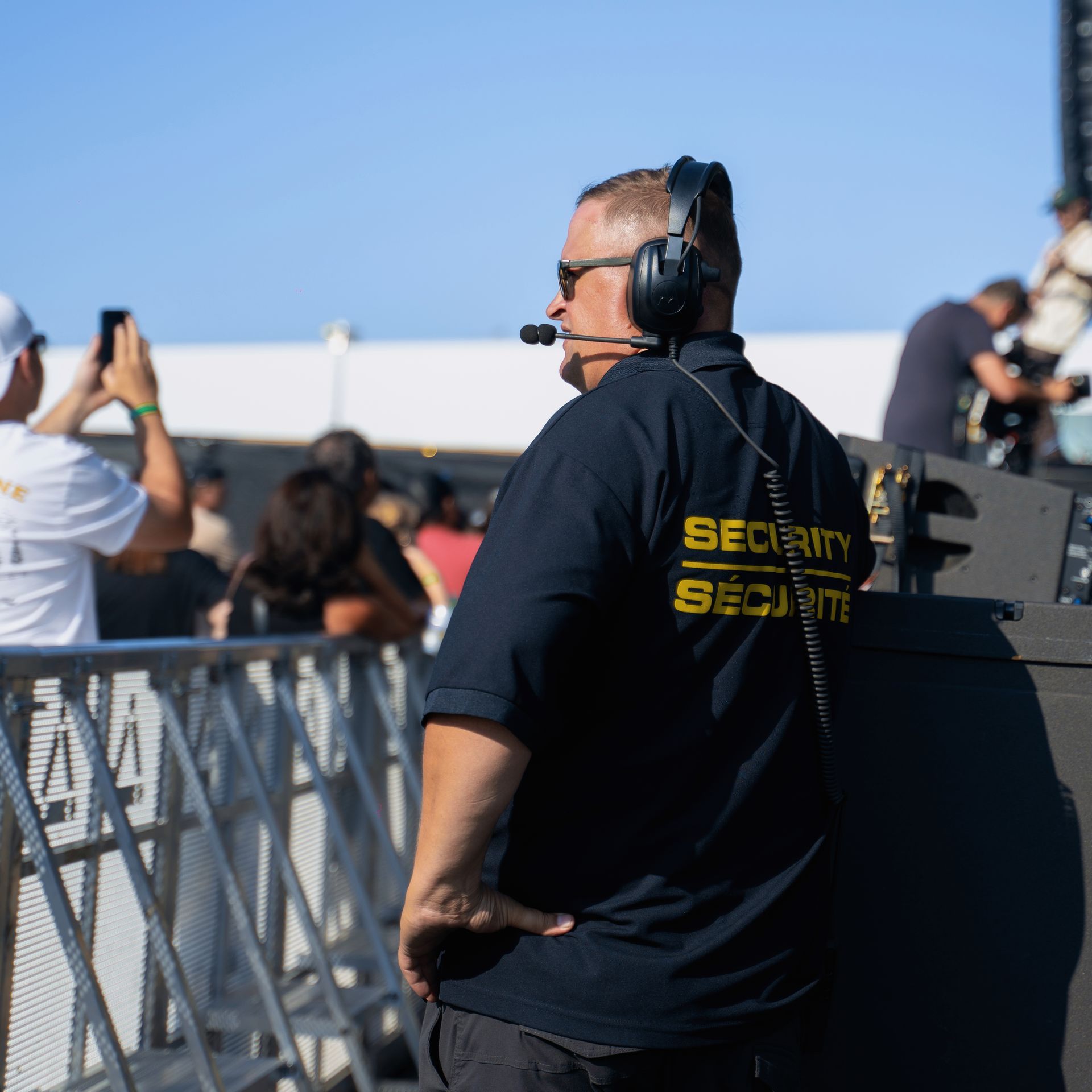 A man wearing headphones and a security shirt