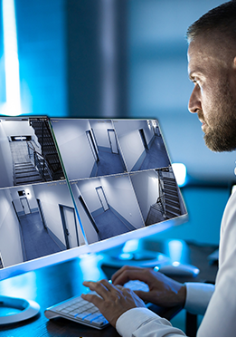A man is looking at security cameras on a computer screen.