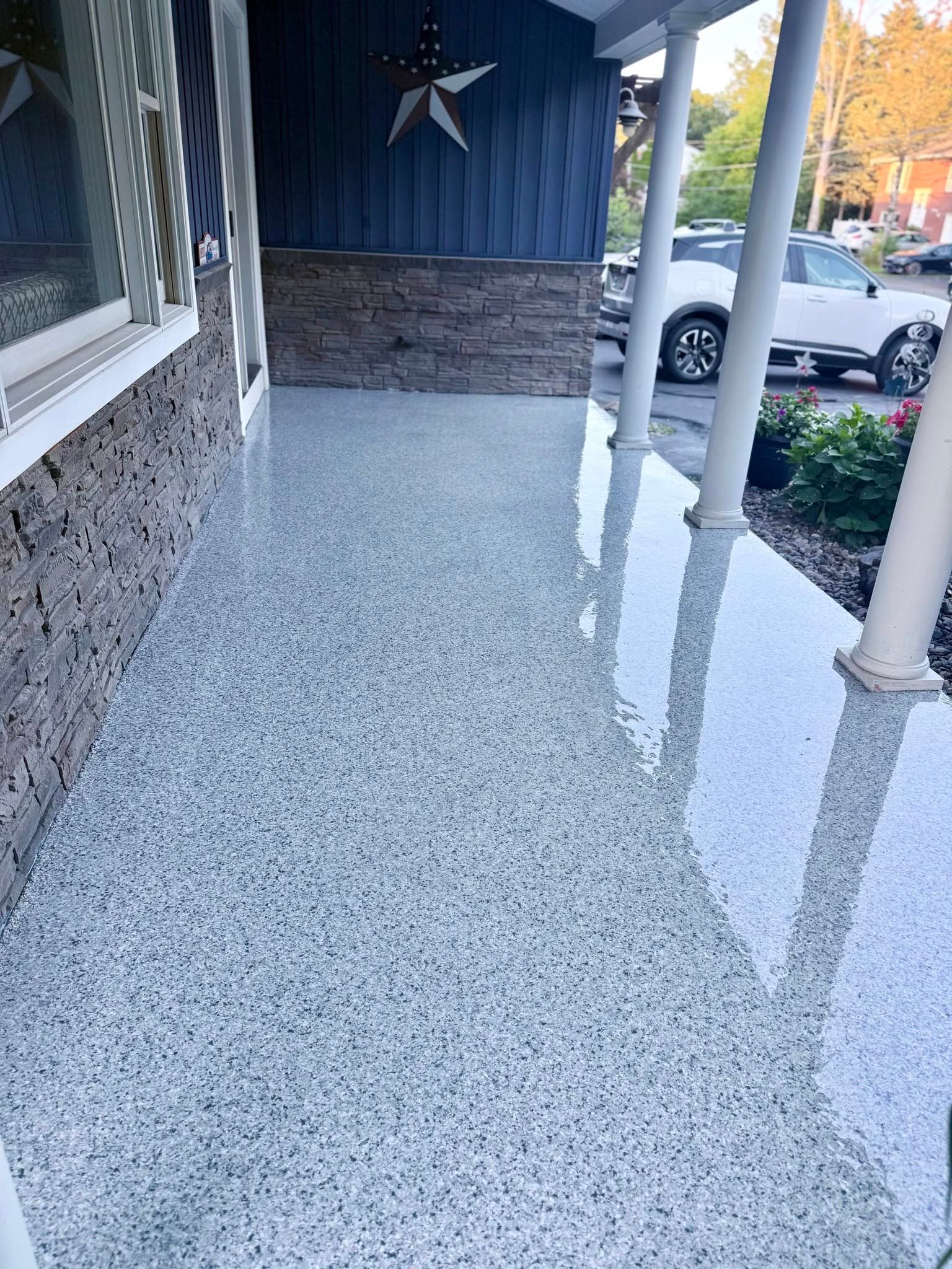 Front porch with speckled concrete floor, white columns, and a view of parked cars outside.