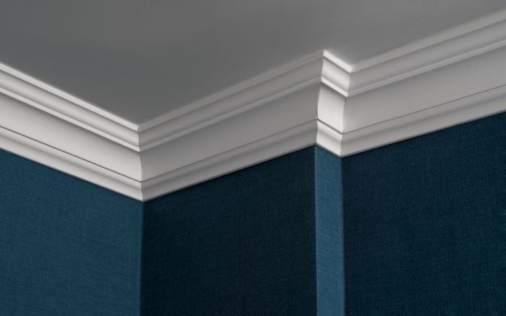 White crown molding on a dark blue corner wall and ceiling.
