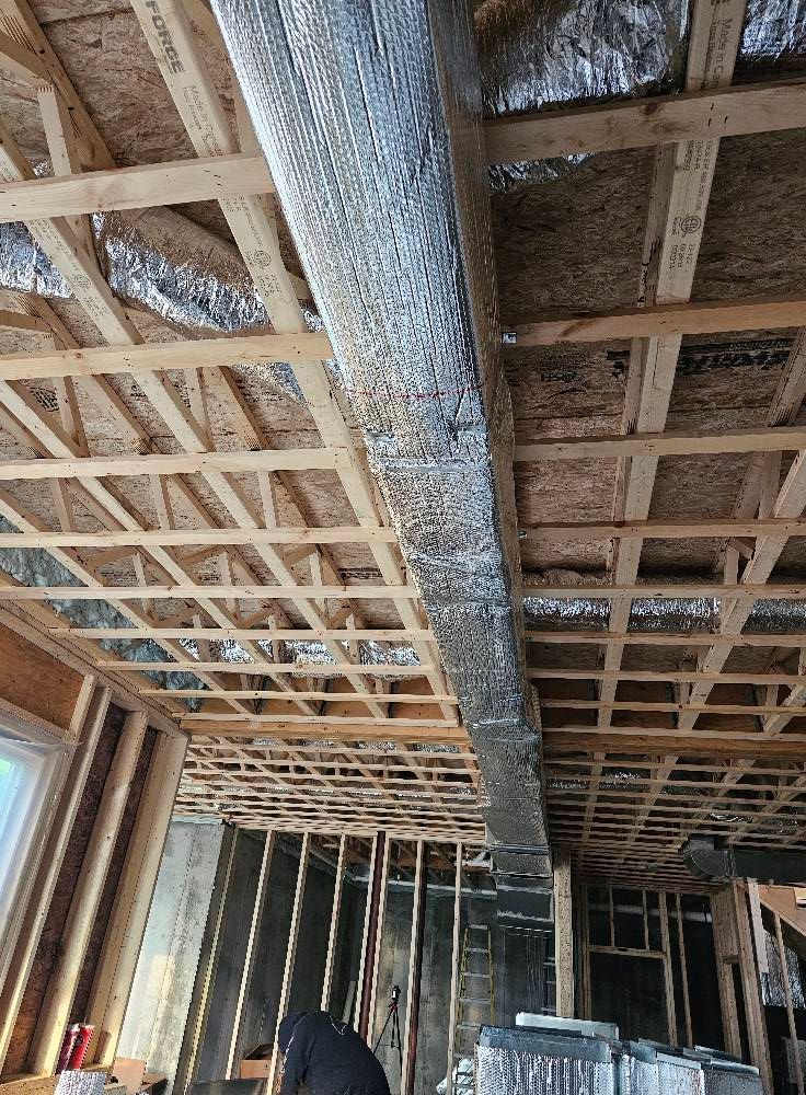Interior view of exposed wooden framing with HVAC ductwork running through the ceiling.