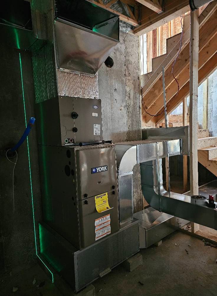 HVAC unit in a basement. Ductwork and stairs are visible. A green laser level line is present.