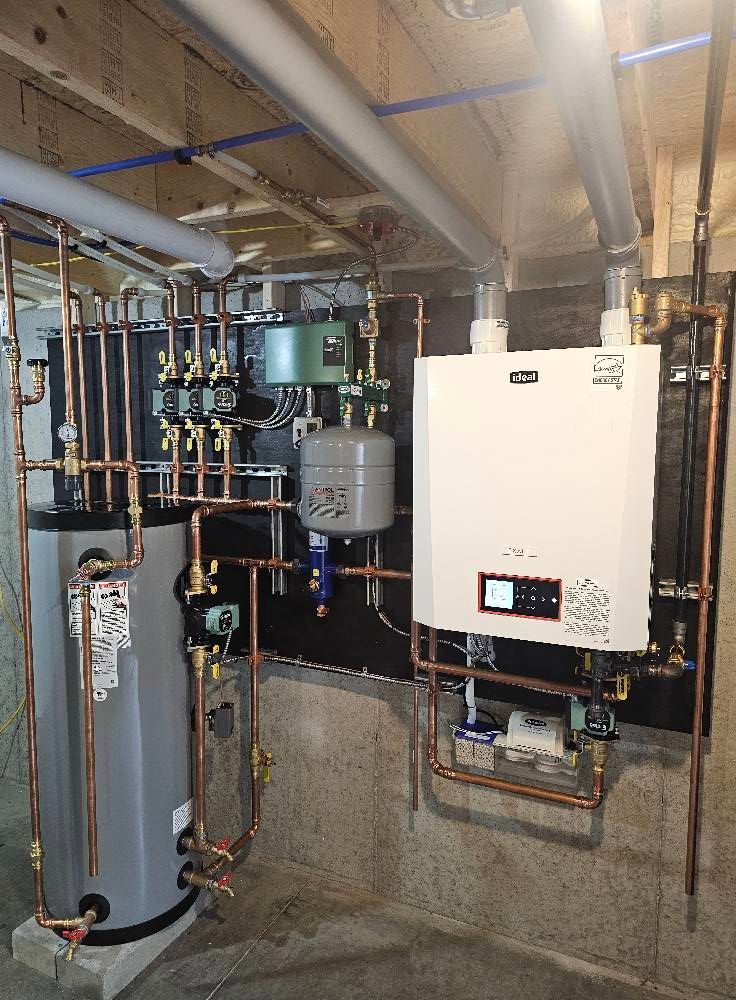 Plumbing system with water heater, boiler, and pipes against a black wall. Copper pipes and various components are visible.