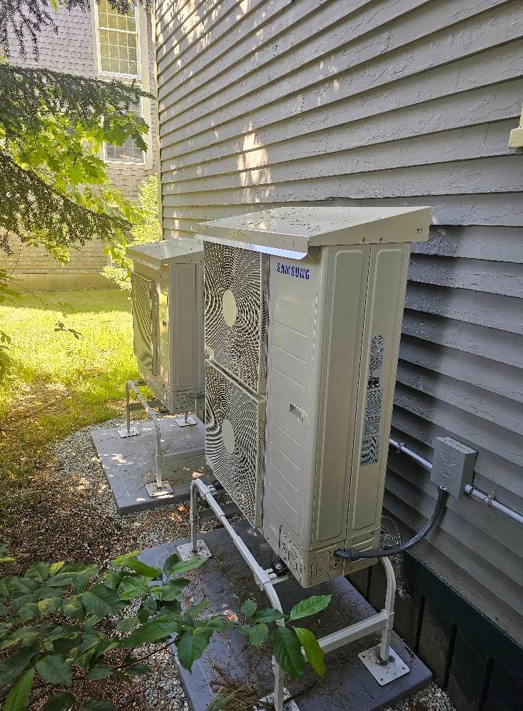 Two beige HVAC units with protective covers mounted on a building's side.