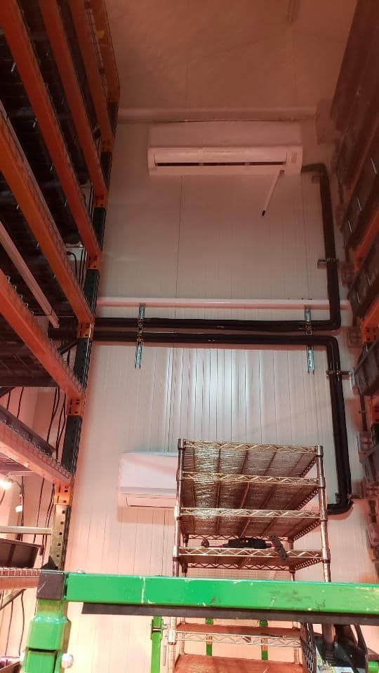 Warehouse interior with metal shelving, air conditioning unit, and sprinkler system.