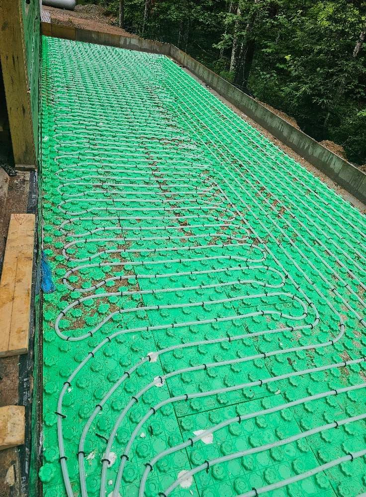Green radiant floor heating system installed on a sloped surface, ready for concrete.