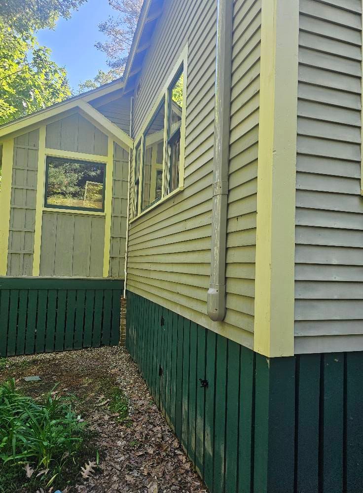 Side view of two connected buildings, painted light green with yellow trim and dark green base.