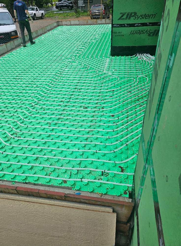 Green radiant floor heating system installation with a person standing nearby.