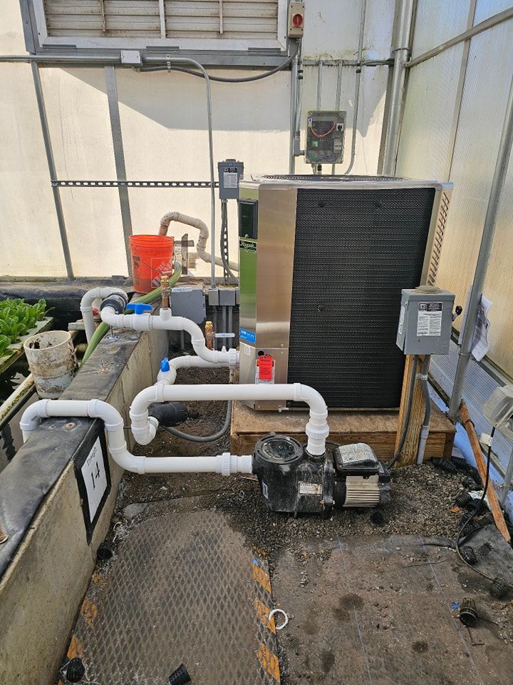 Hydroponic system in a greenhouse with pipes, pump, and a cooling unit.