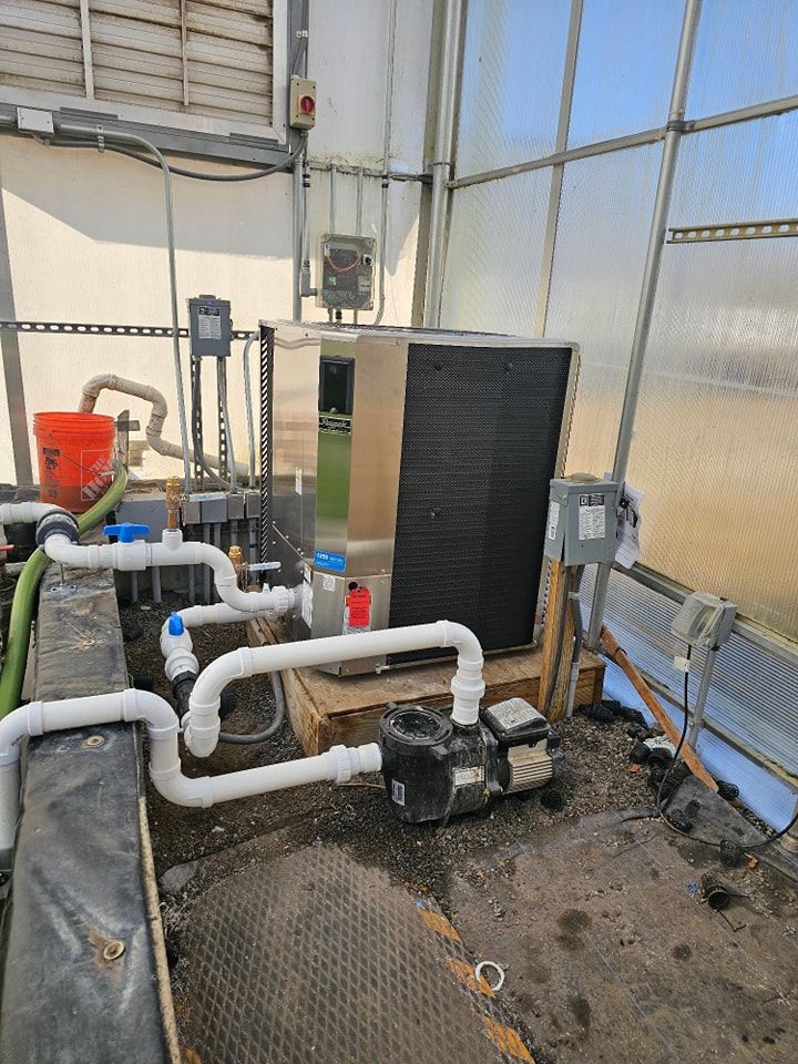 Water pump system in a greenhouse with pipes, a cooling unit, and control panels.