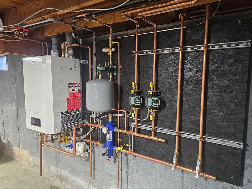 Copper plumbing and boiler system on a concrete basement wall.