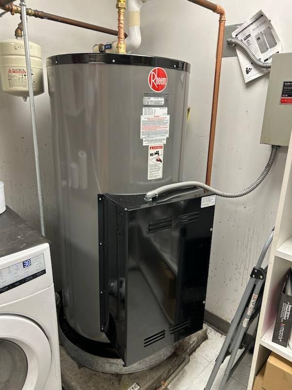 Gray Rheem water heater in a utility room, connected to copper pipes and electrical wiring.