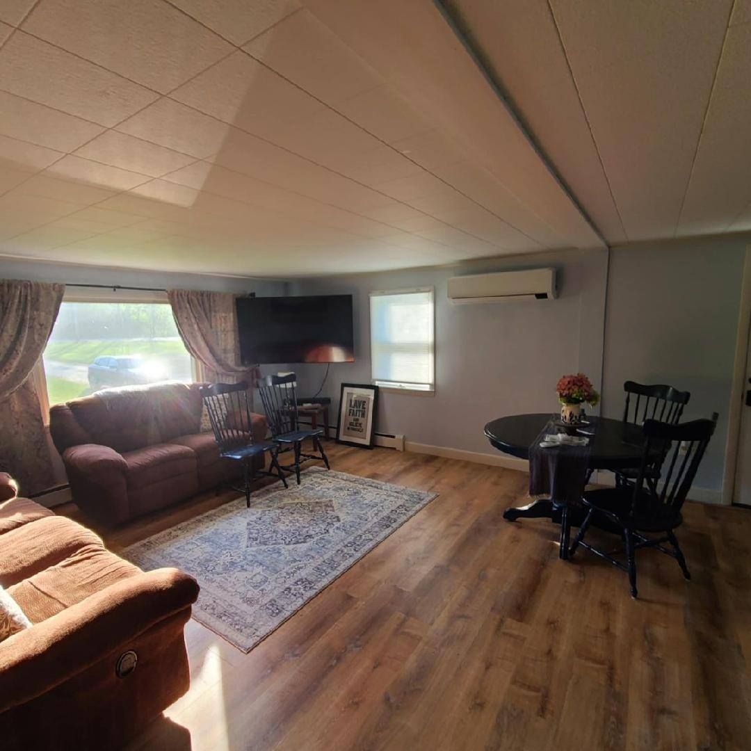 Living room with a sofa, rug, dining table, and mounted TV.