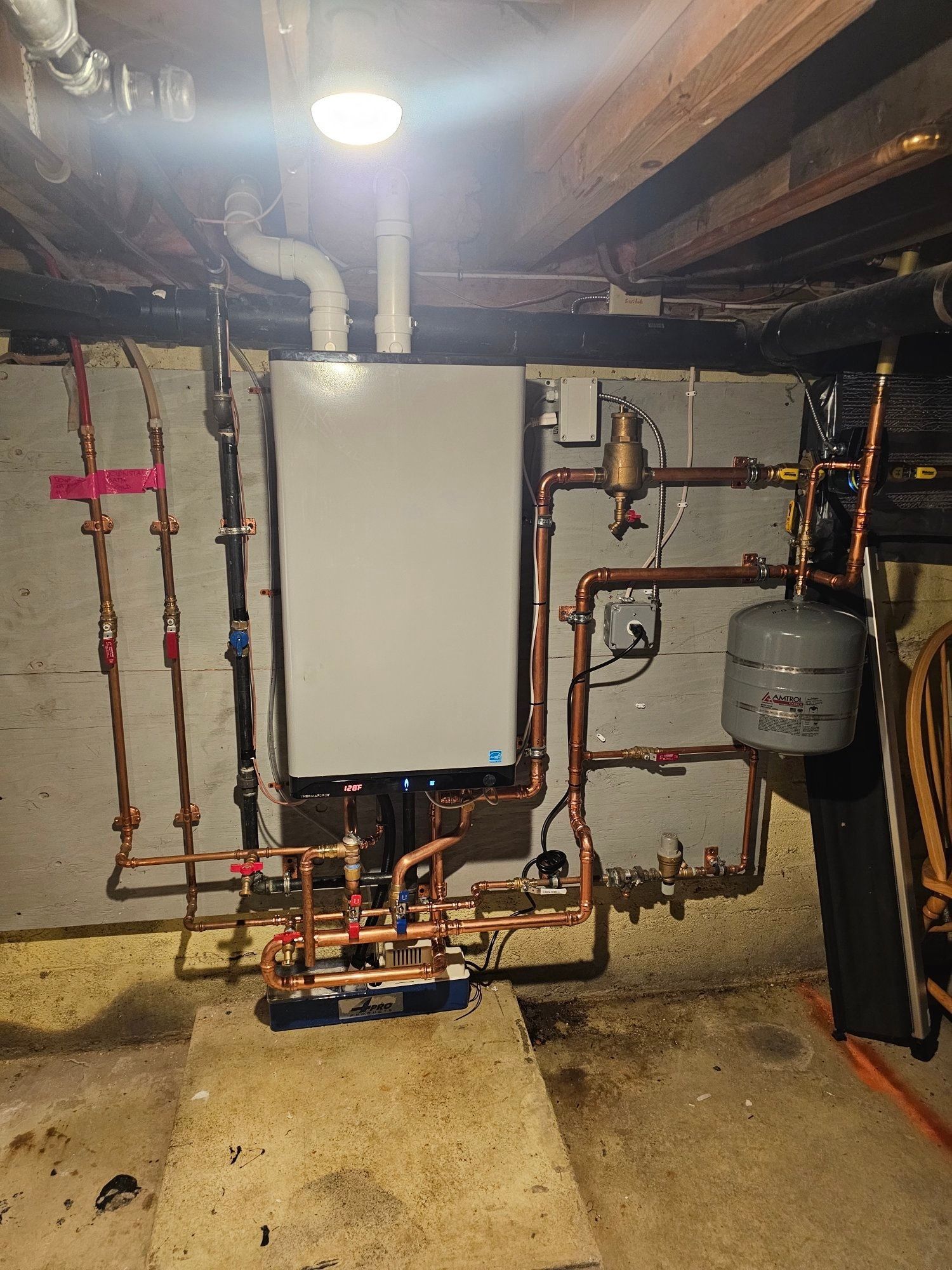 A modern gas boiler with copper pipes installed in a basement.