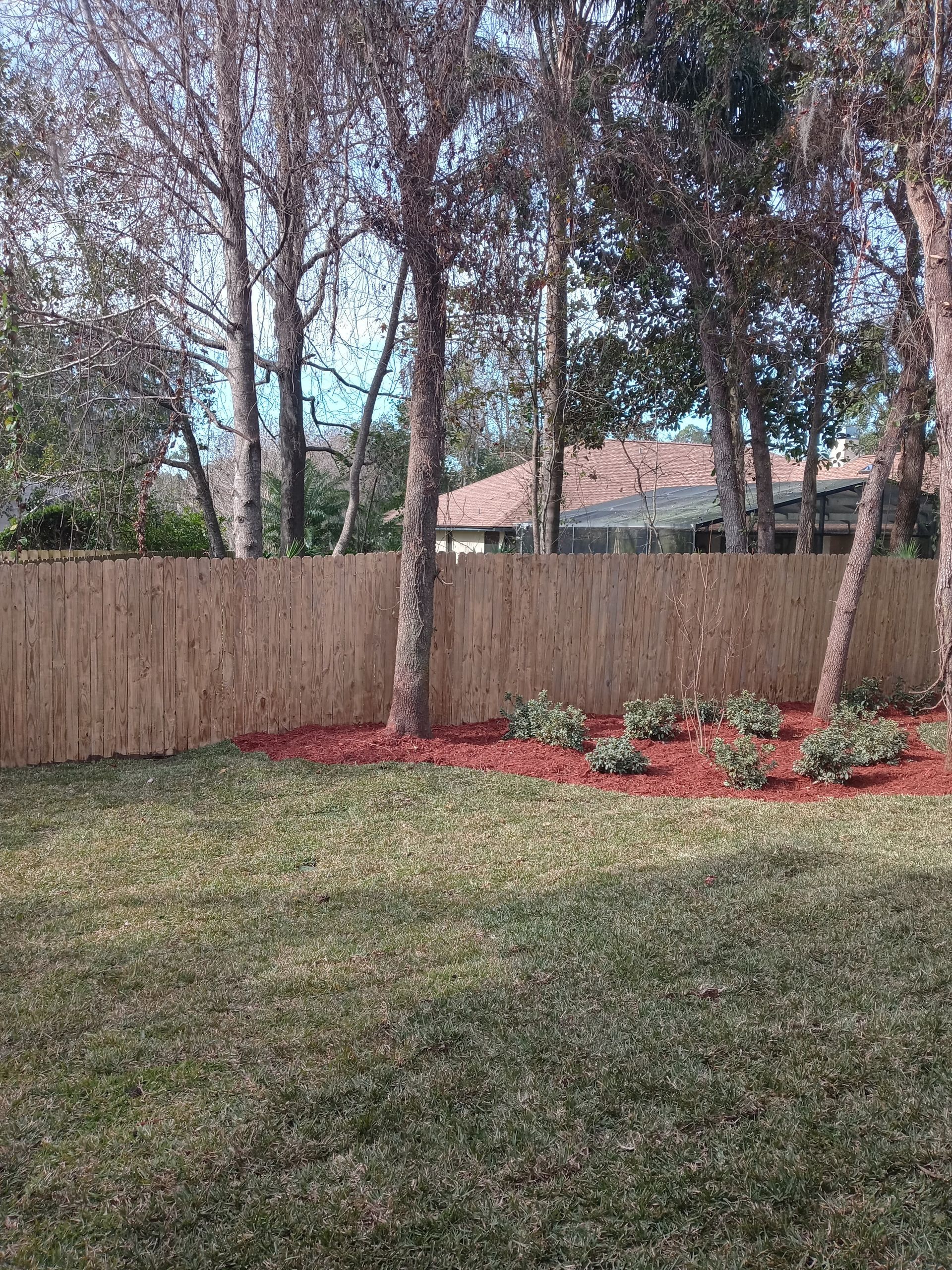 A backyard with a wooden fence and trees in the background.