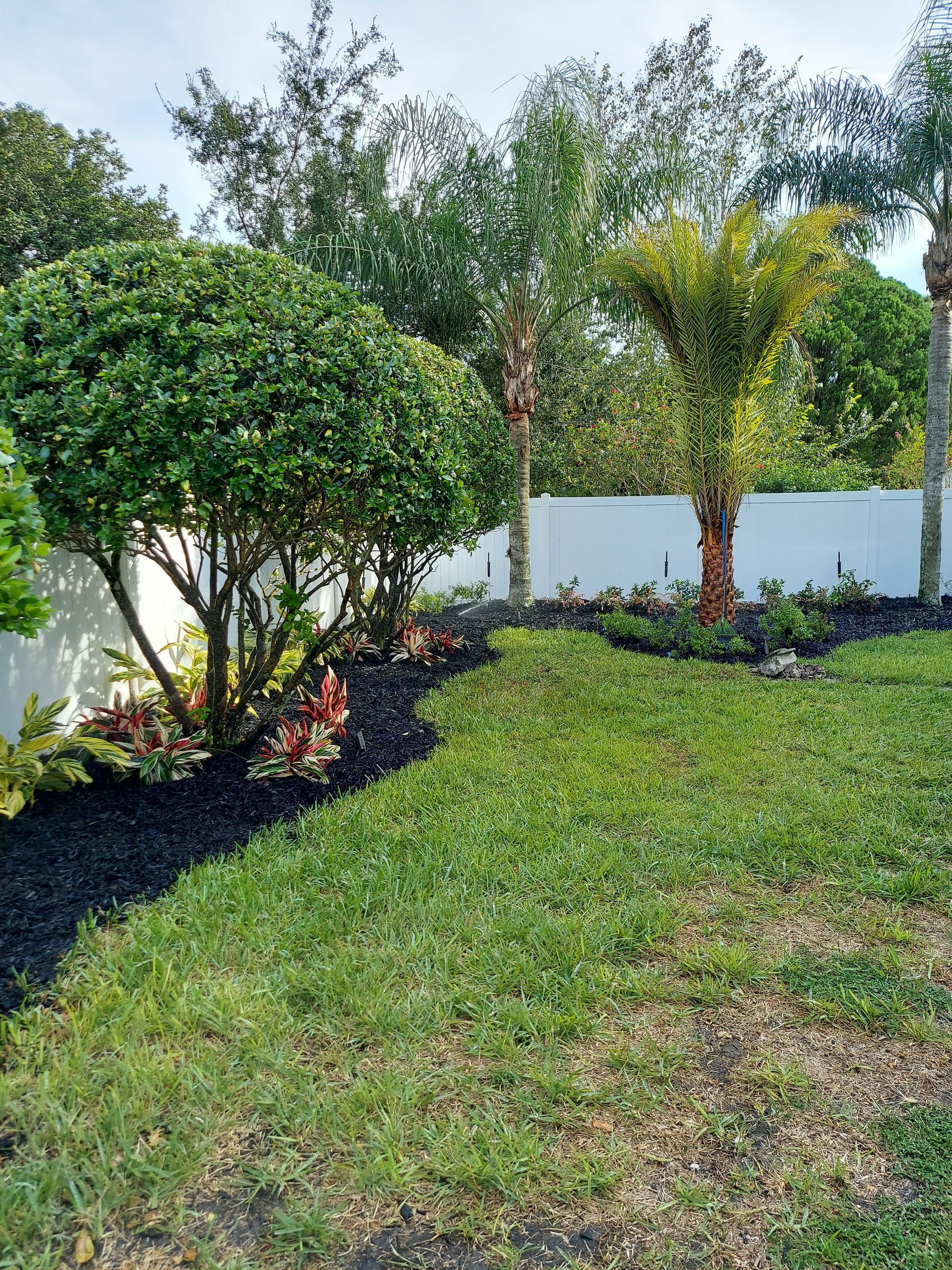 Two men are installing artificial grass in a backyard.