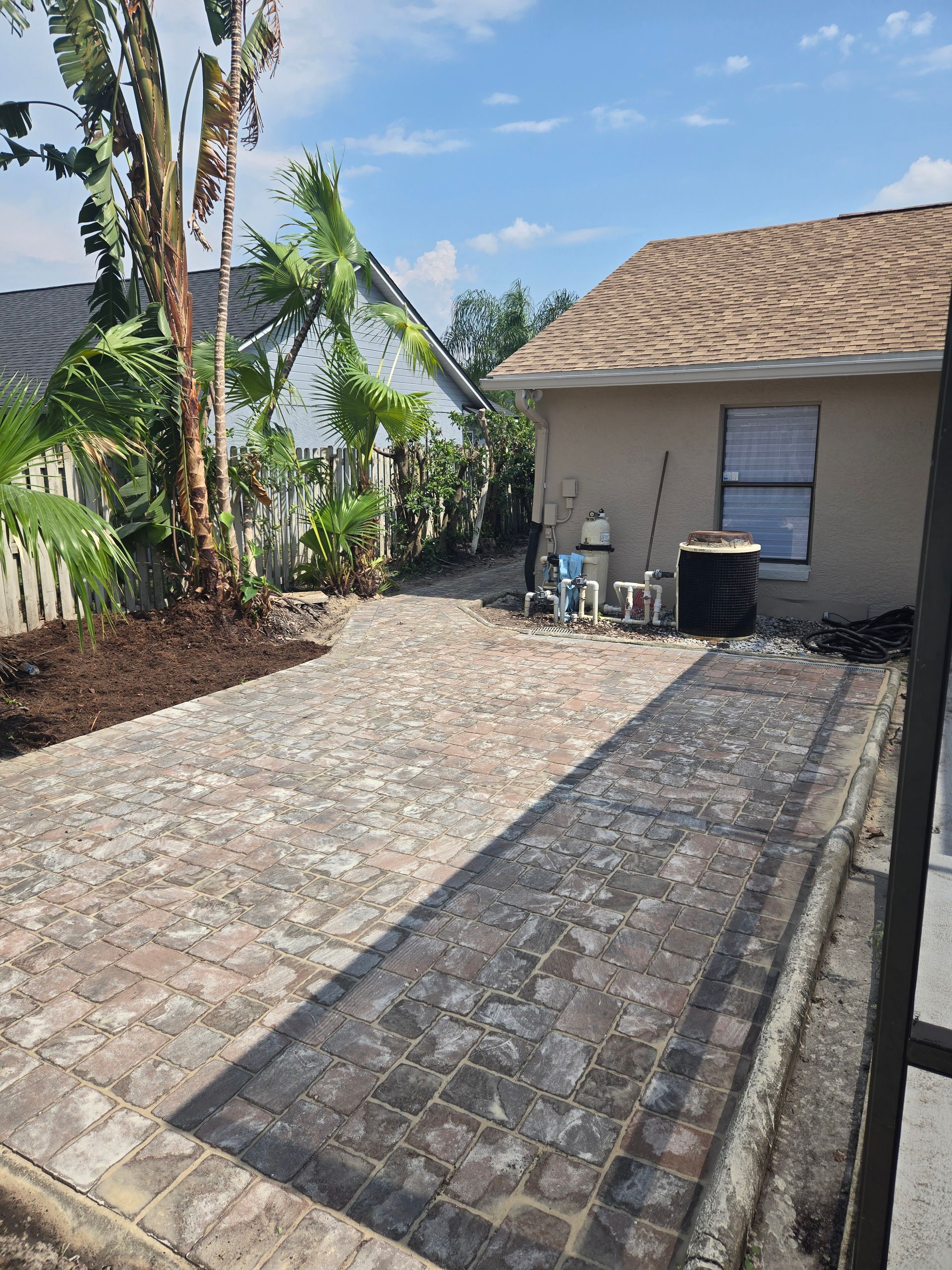A brick driveway leading to a house in the woods.