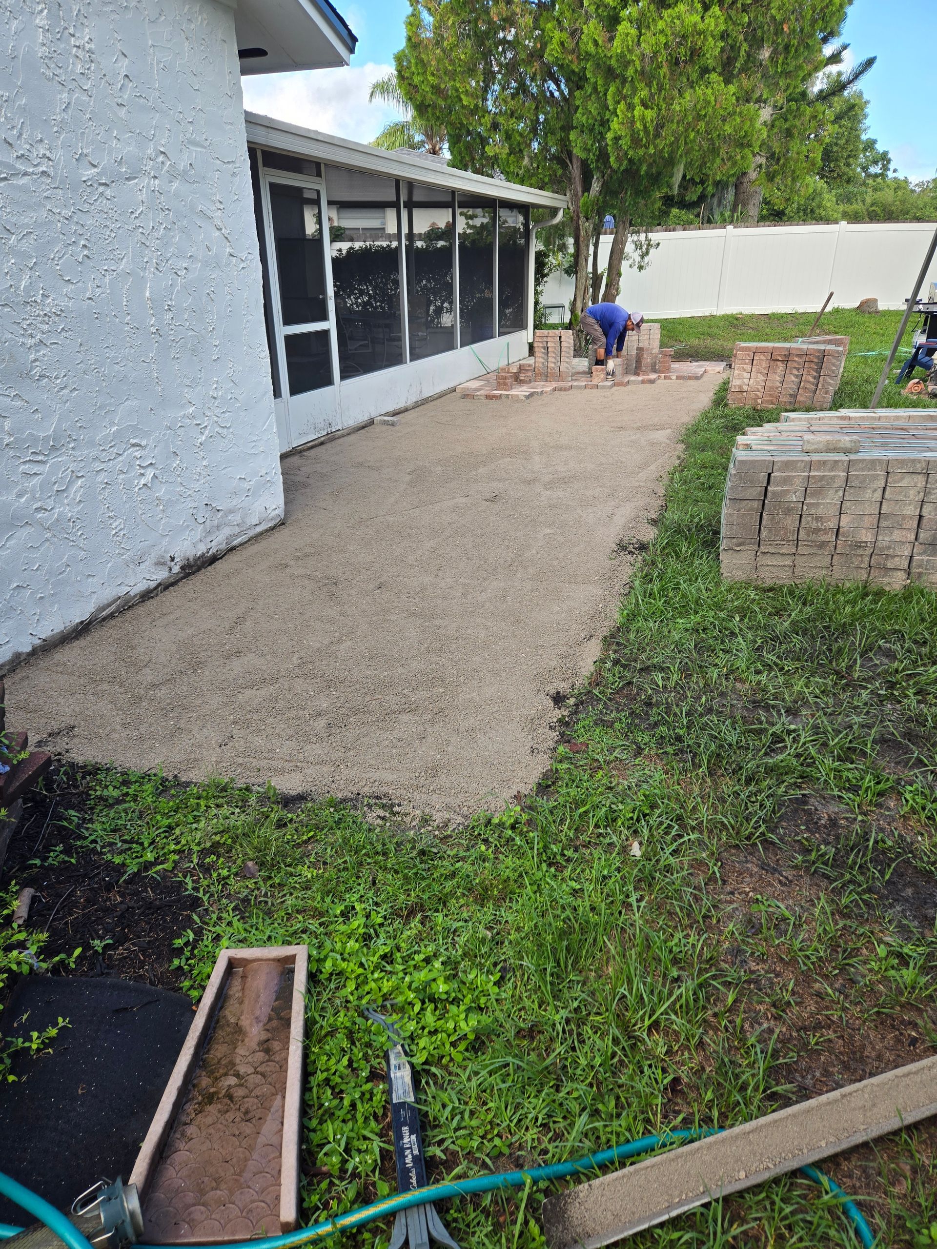 A man is working on a patio in front of a house.