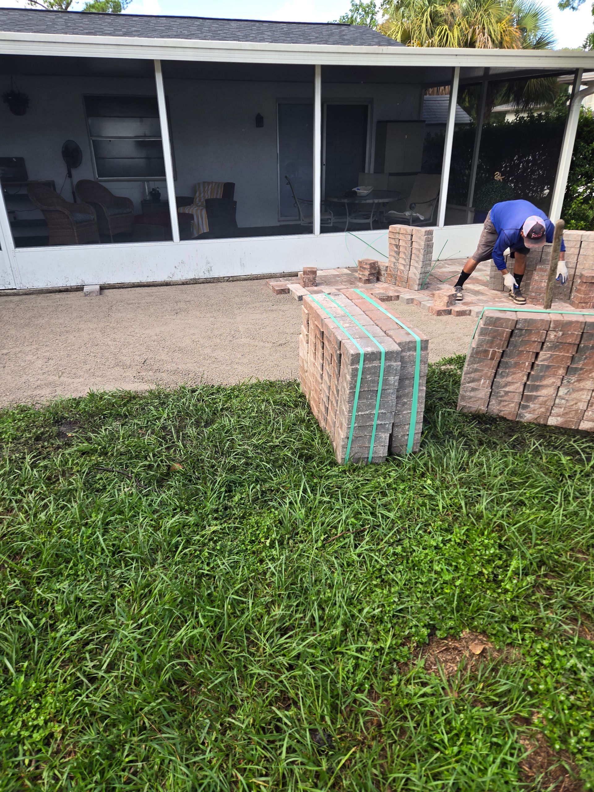 A man is working on a patio in front of a house.
