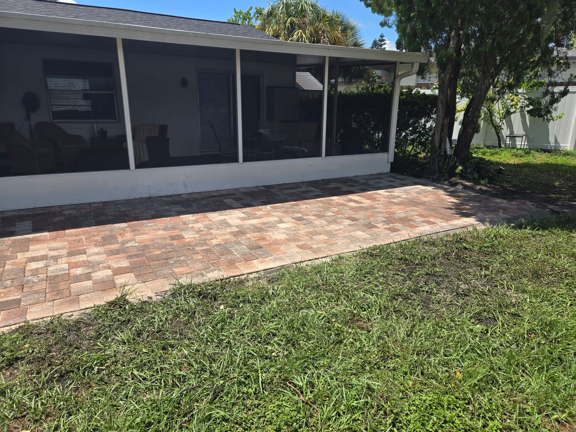 A house with a screened in porch and a brick walkway in front of it.