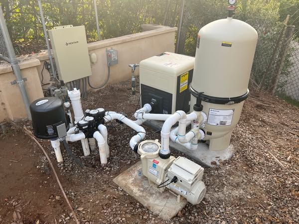 A swimming pool pump and filter are sitting on the ground.
