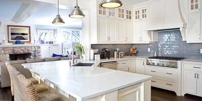 A kitchen with white cabinets , granite counter tops , stainless steel appliances and a large island.