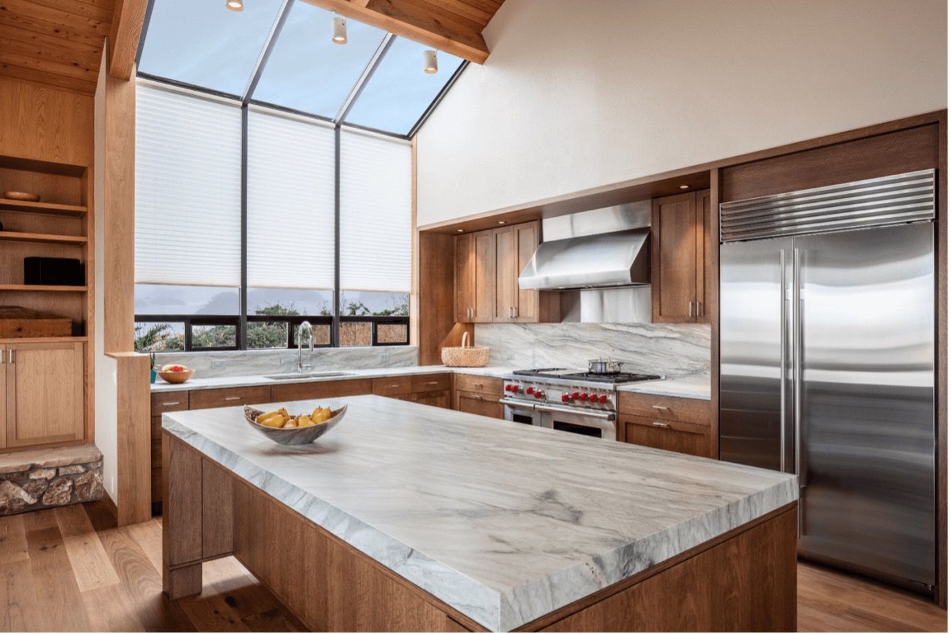 Modern kitchen with marble island, wood cabinetry, stainless steel appliances, and large windowed wall in Cincinnati, OH