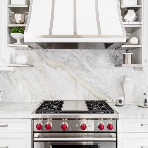 A kitchen with a stove top oven and a hood above it