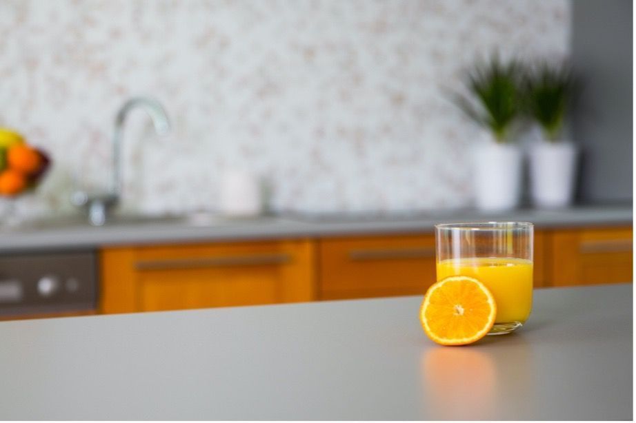 A glass of orange juice and an orange slice on a kitchen counter.