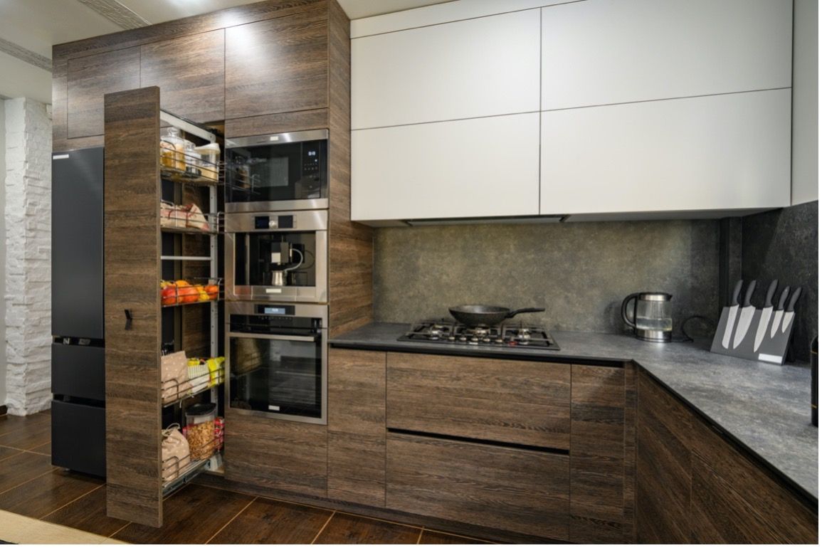 A kitchen with wooden cabinets , white cabinets , stainless steel appliances and a pantry.