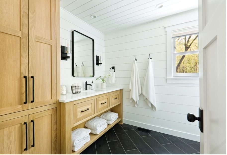 A bathroom with a sink , mirror , cabinets and towels.