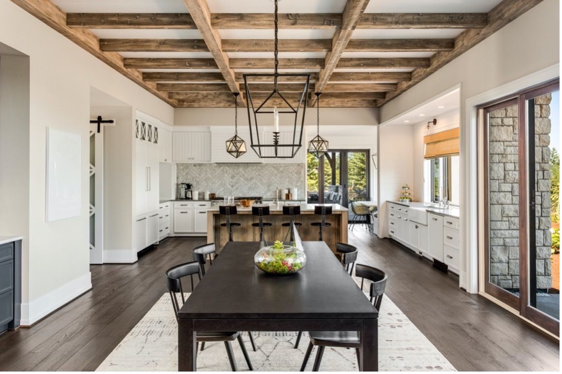A dining room with a table and chairs and a kitchen in the background.