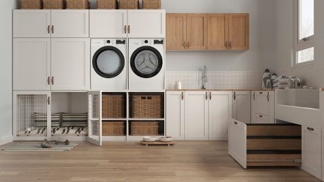 A laundry room with a washer and dryer and a dog cage.