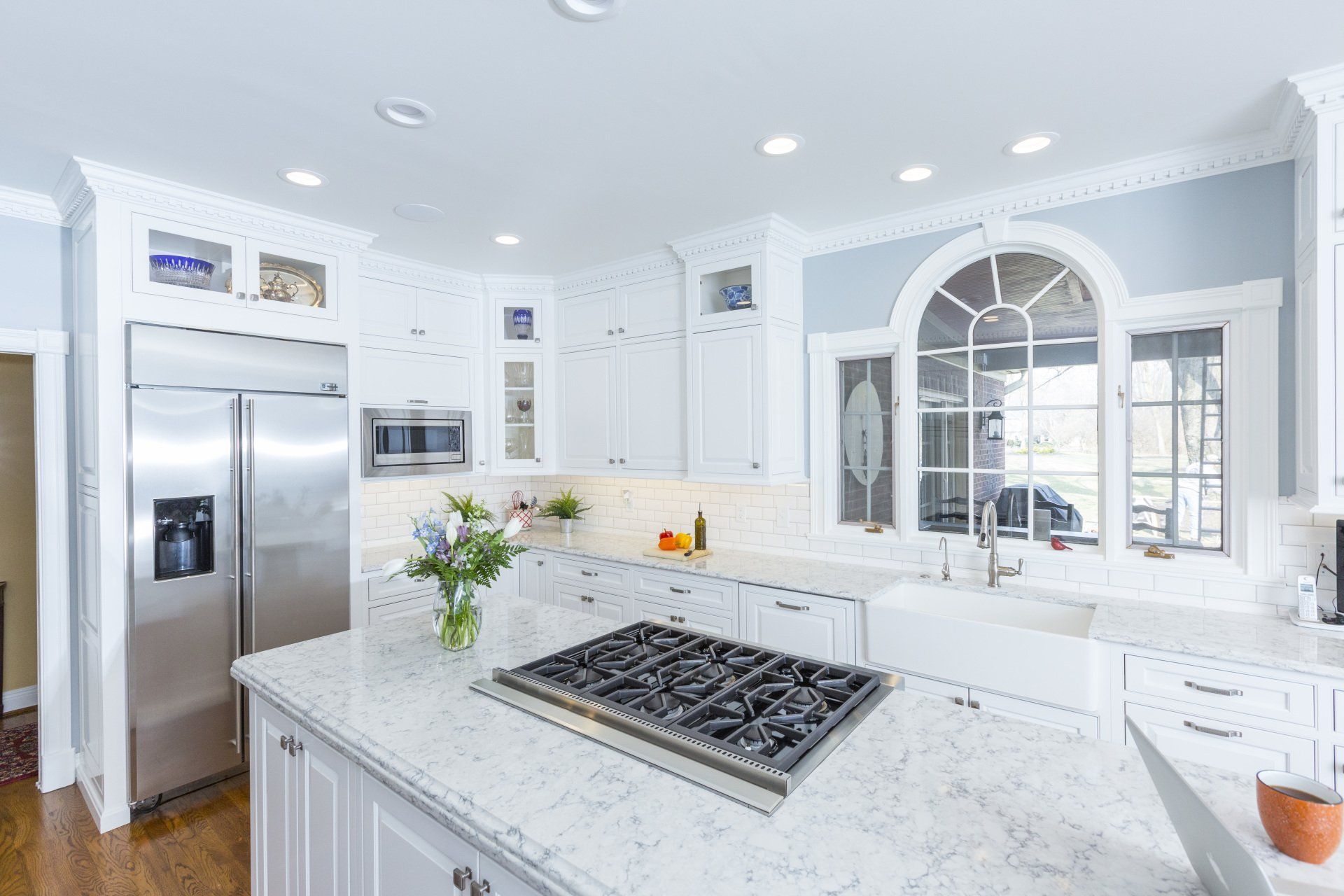 A kitchen with white cabinets , stainless steel appliances , a stove top oven and a sink.