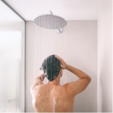 A man is taking a shower in a bathroom.