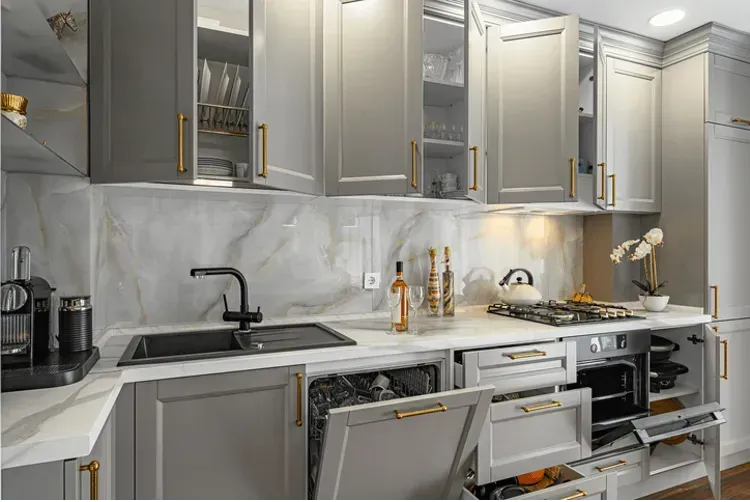 A kitchen with gray cabinets , white counter tops , a sink , and a dishwasher.
