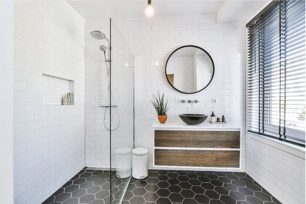 A bathroom with a walk in shower , sink , mirror and window.