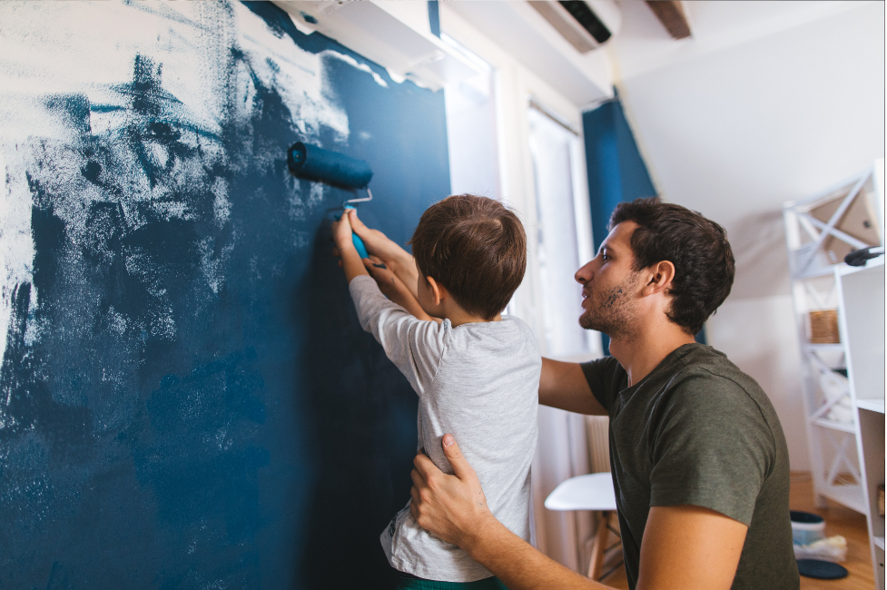 A man and a child are painting a wall together.
