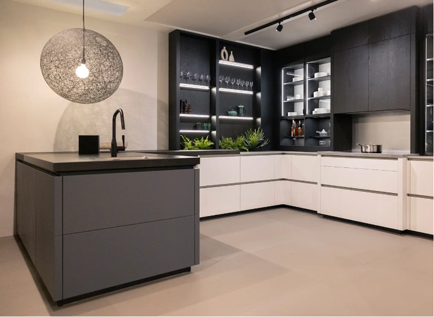 A kitchen with black and white cabinets and a large island in the middle.