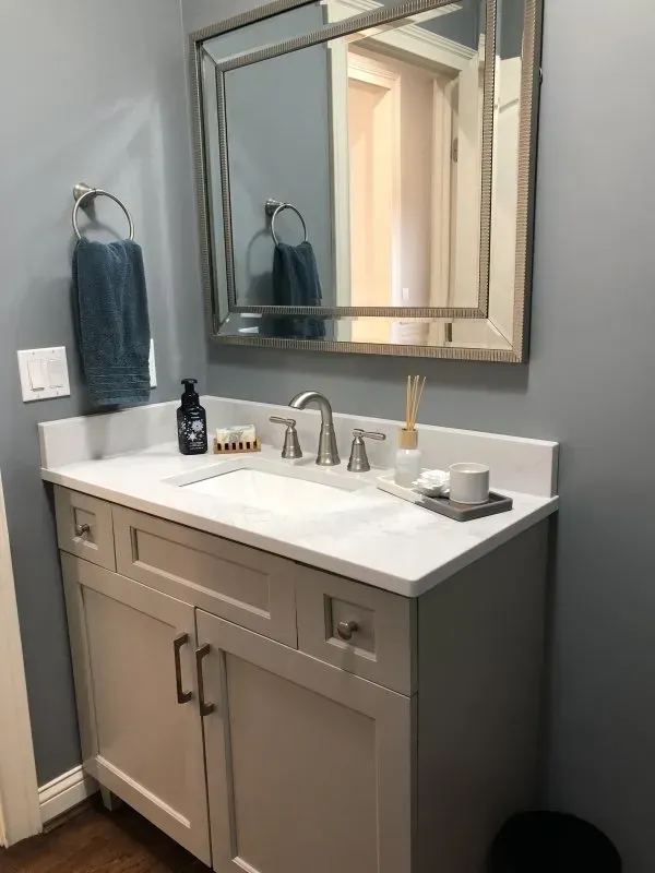 A bathroom with a sink , mirror and towel rack.