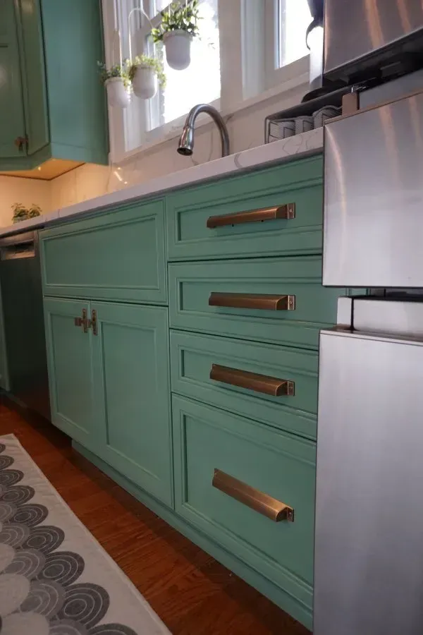 A kitchen with green cabinets and stainless steel appliances.