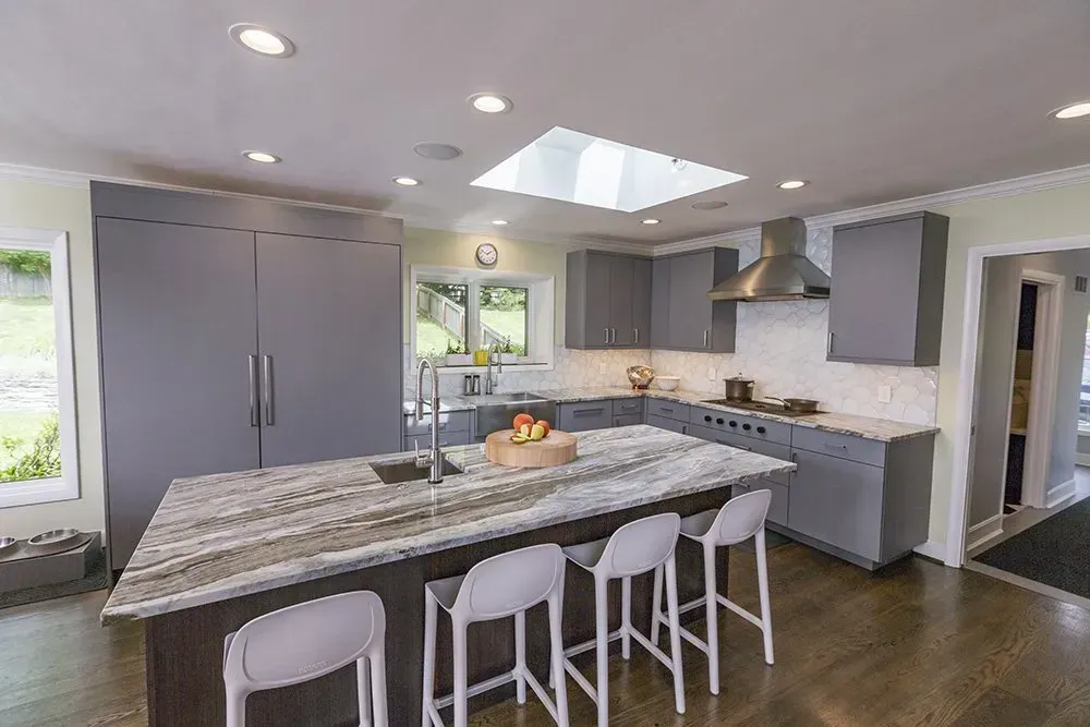 A kitchen with a large island , stools and a skylight.