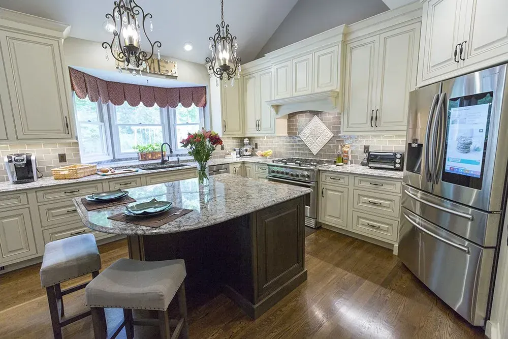 Bright kitchen with granite island, white cabinets, stainless fridge, and large window over the sink. In Cincinnati, OH