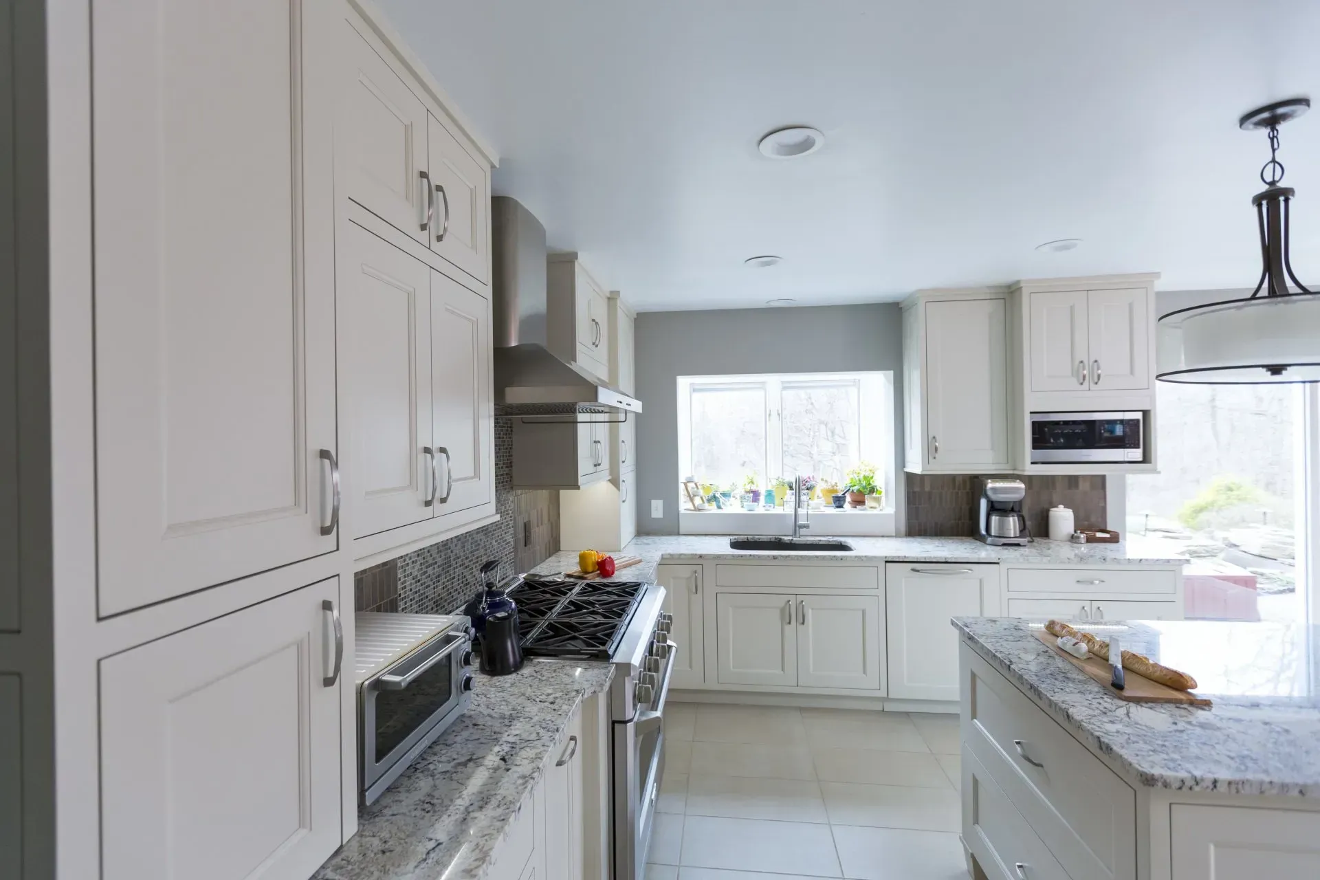 Bright white kitchen with granite counters, stove, island, and sunlight from a window in Cincinnati, OH 