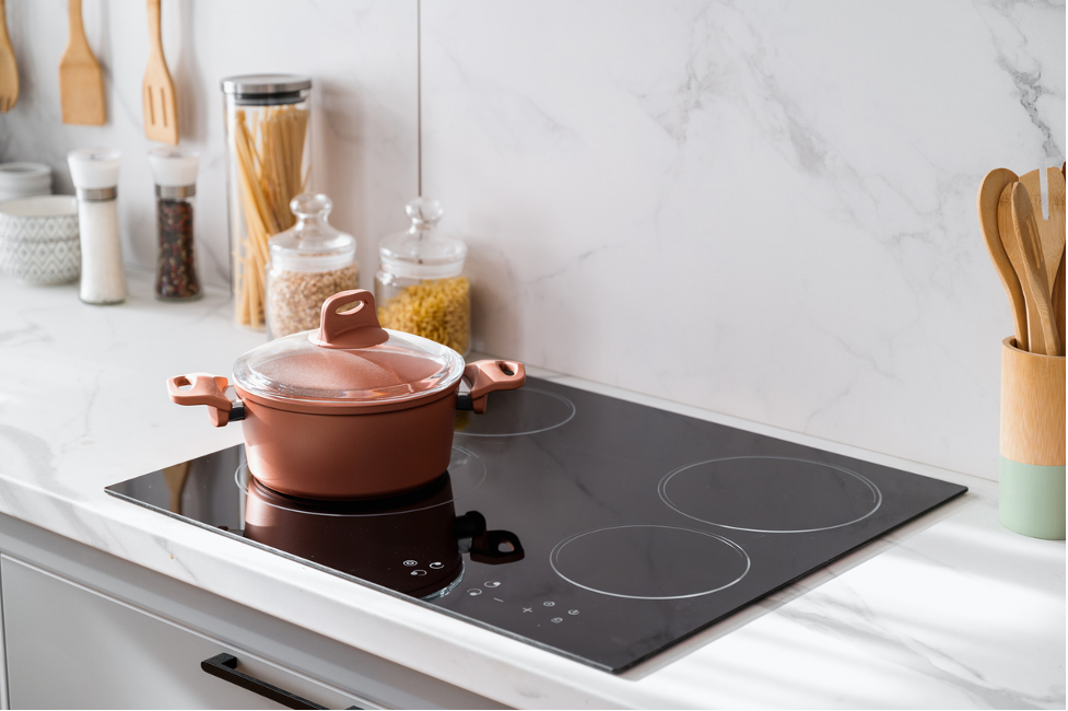 A pot is cooking on an induction stove in a kitchen.