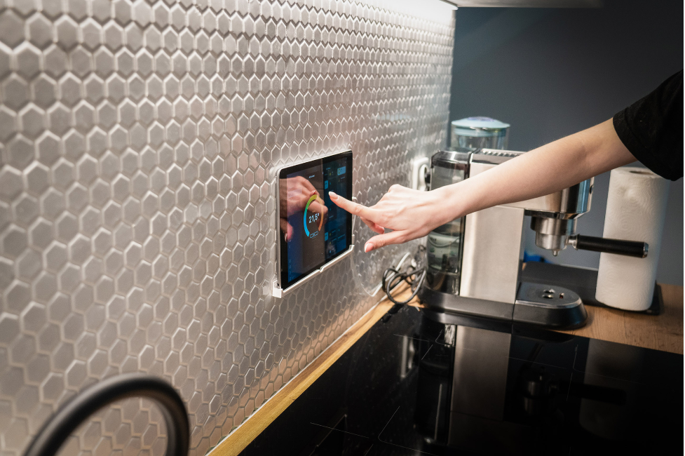 A person is touching a tablet on a kitchen counter.